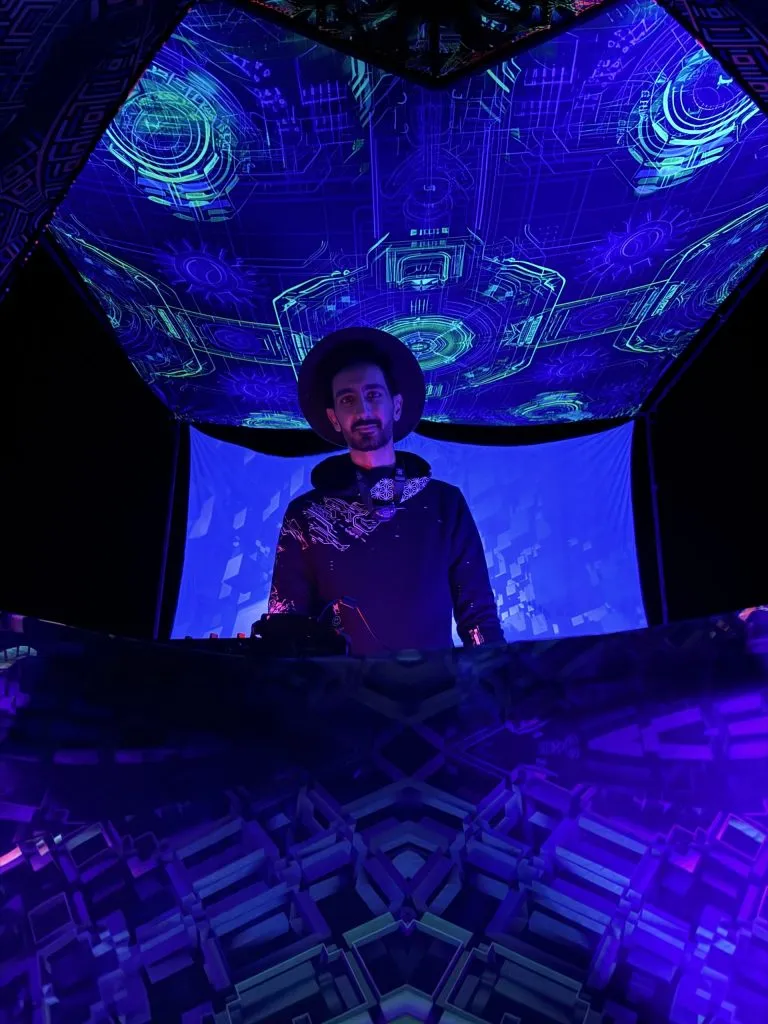 KOOROW behind the decks at a psychedelic music event